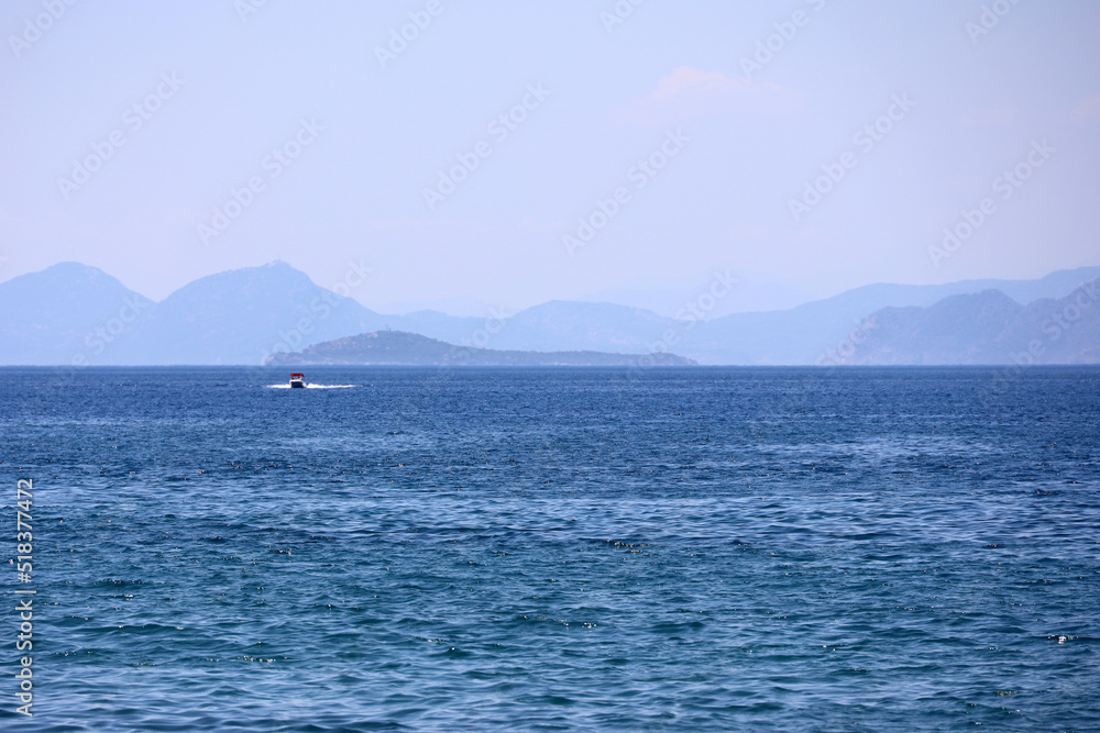 Picturesque view to blue sea and mountain coast on horizon in mist. Calm water surface, background for traveling and vacation