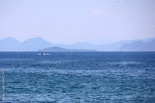 Picturesque view to blue sea and mountain coast on horizon in mist. Calm water surface, background for traveling and vacation © Oleg
