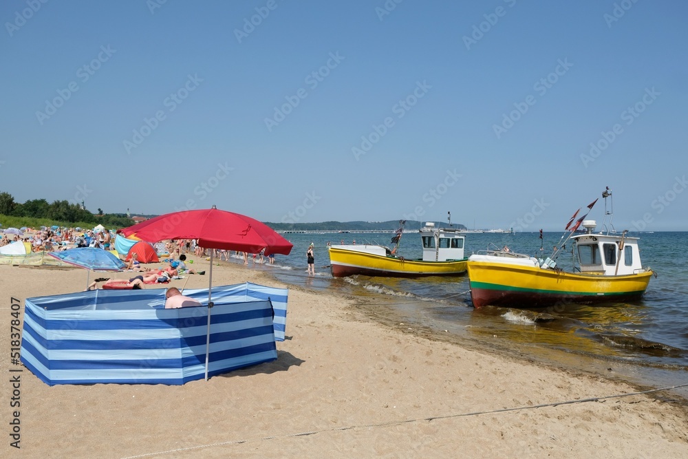 Colorful screen with umbrella on beach by sea. Two fishing boats standing by beach. Baltic Sea, Sopot, Poland