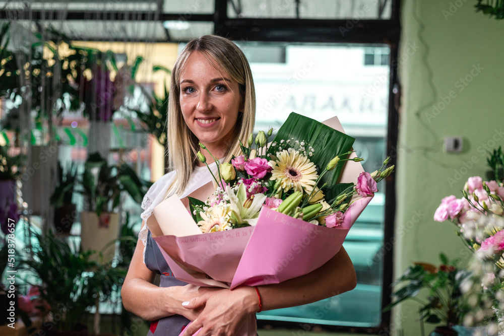 Smiling woman florist small business flower shop owner, at counter, self employed concept.