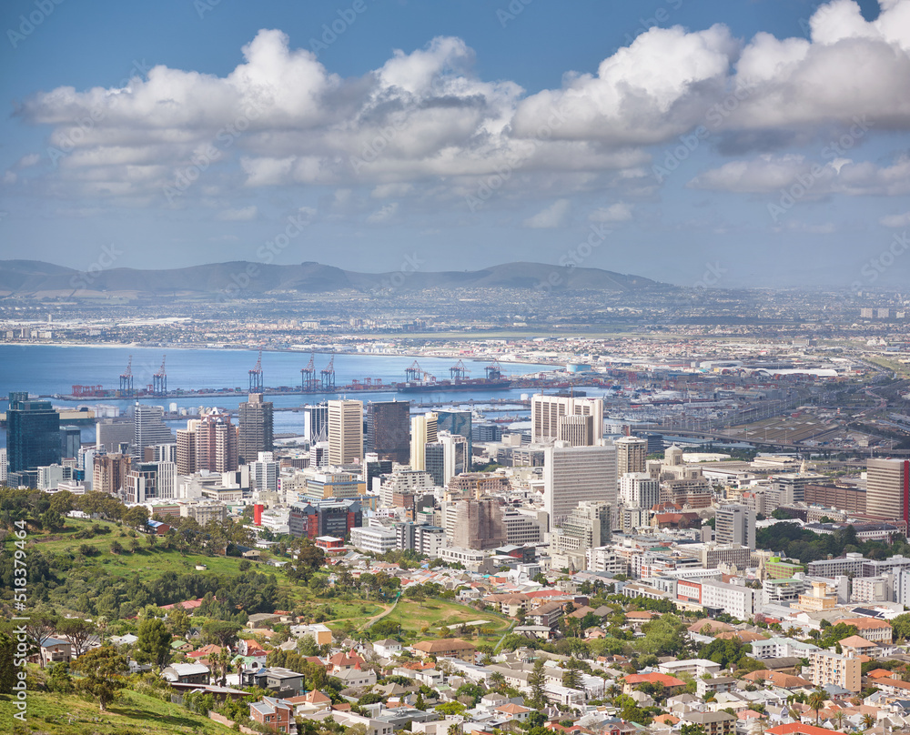 Landscape of buildings in an urban town with greenery along the mountain and sea. Copy space with views from Signal Hill in Cape Town, South Africa of a cloudy blue sky over a beautiful coastal city