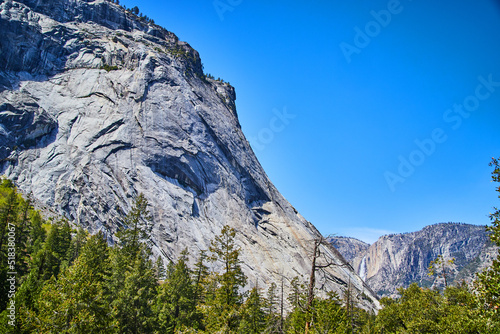 Valley of Yosemite with pine tree forest and waterfall in distance