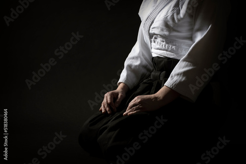 Aikido sitting pose in hakama uniform on black background. Shallow depth of field. SDF. photo