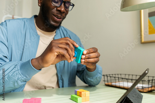 Black man making wooden geometric puzzle in office