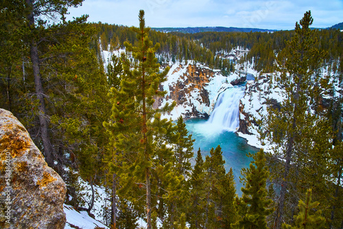 Yellowstone in winter at stunning lower falls through pine trees photo