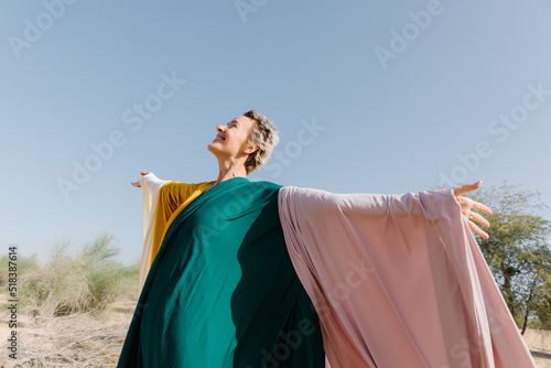  A woman with colourful pieces of fabric outdoors smiling to the sky