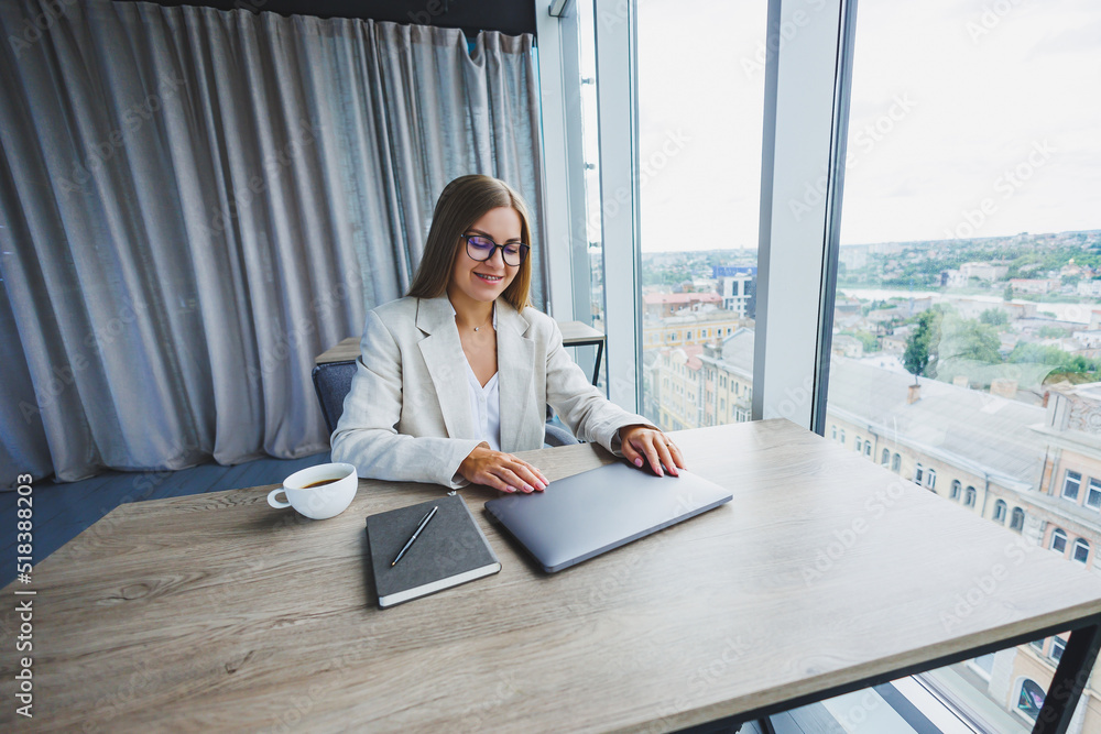 Successful young female manager in an elegant casual jacket and optical glasses, sits in the office at the workplace, an experienced woman with a modern laptop, working in the office Successful young female manager in an elegant casual jacket and optical glasses, sits in the office at the workplace, an experienced woman with a modern laptop, working in the office