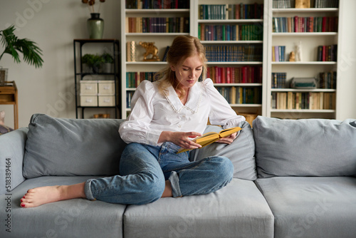 Woman reading book in living room photo