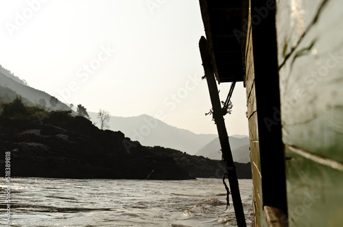 A long boat travels a river in Laos photo