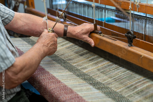 Konstfotografi master craftsman working on a traditional wooden loom and hand weaving woollen h