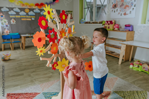 Toddler girl and boy playing with flowers from felt indoors photo
