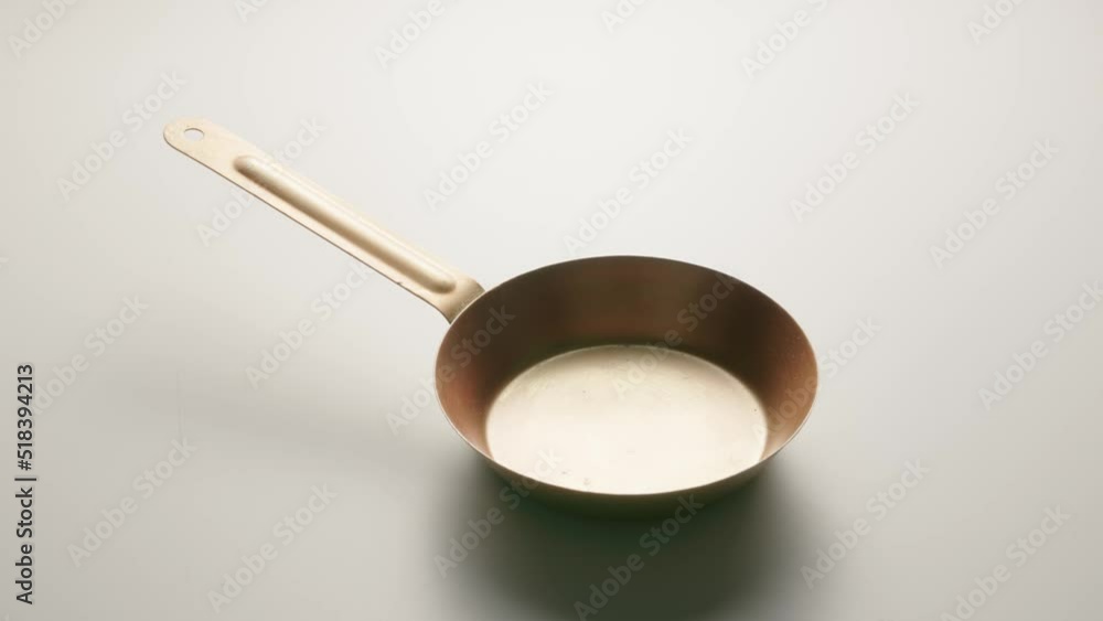 Copper fryingpan spinning on on a light gray studio background. Round empty stainless or aluminum pan with handle. Kitchenware, utensils for cooking and frying, interior decoration. Copper fryingpan spinning on on a light gray studio background. Round empty stainless or aluminum pan with handle. Kitchenware, utensils for cooking and frying, interior decoration.