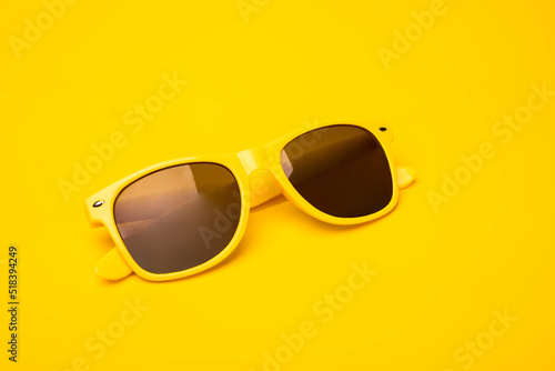 Yellow fancy sunglasses on a vibrant sunny background. Summertime, travel concept, banner with a copy space.