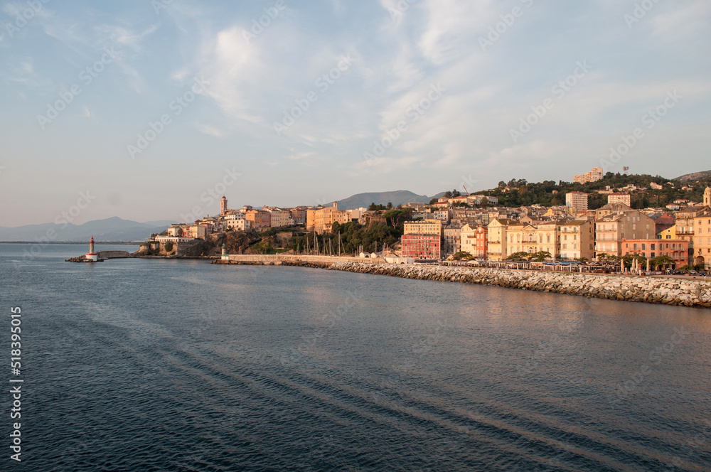 The city of Bastia illuminated by the morning sun, whose buildings and waterfront are reflected in the sea