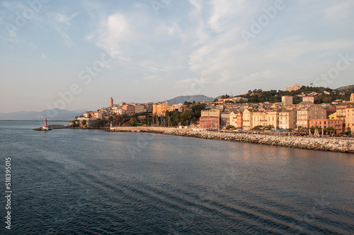 The city of Bastia illuminated by the morning sun, whose buildings and waterfront are reflected in the sea © Jan