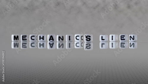 mechanic's lien word or concept represented by black and white letter cubes on a grey horizon background stretching to infinity