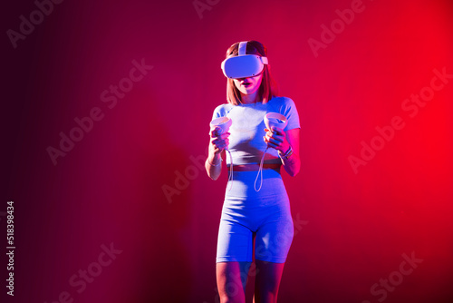 Video Gaming Concept. women playing with virtual reality goggles, VR headset, modern technology glasses  with neon light  on a colored background