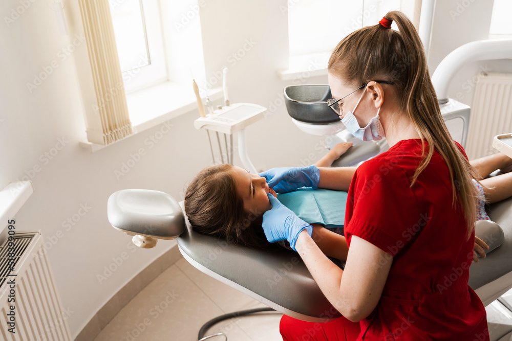 Consultation with pediatric dentist in dentistry. Pediatric dentist examines teeth of child girl for treatment of toothache. Pain in teeth in children. Consultation with pediatric dentist in dentistry. Pediatric dentist examines teeth of child girl for treatment of toothache. Pain in teeth in children.