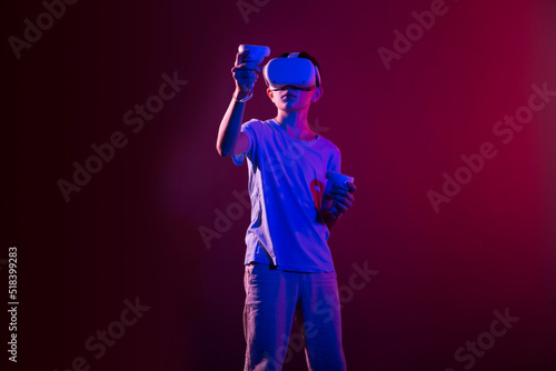 Video Gaming Concept. teenager boy playing with virtual reality goggles, VR headset, modern technology glasses with neon light on a colored background