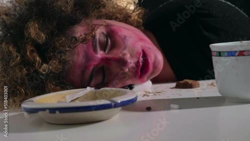young woman brutalized by drugs with her head resting on the table photo