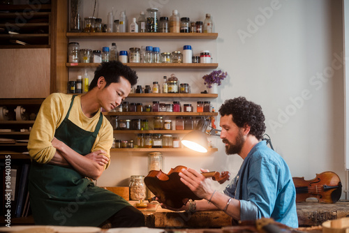 Two violin luthiers discussing about best restoration approach 