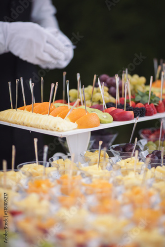 Catering on wedding. Waiters serving table in the restaurant preparing to receive guests. Wedding banquet table. Sweet table with fruit. Fruit bar on party. Delicious fruits appetizers.