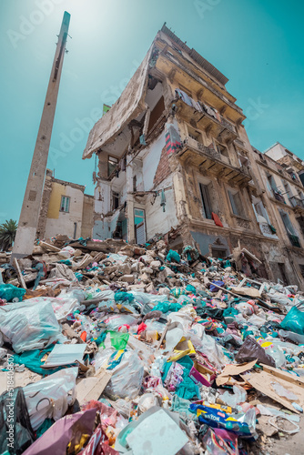 A huge amount of rubbish next to a partially collapsed building in Oran, Algeria on a sunny day. People still live in this house, altough half of it is destroyed. photo