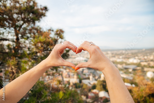 A woman's hand in the shape of a heart on the background of the city of Tbilisi in Georgia. Love, romance, holidays, rest, relaxation, tourists