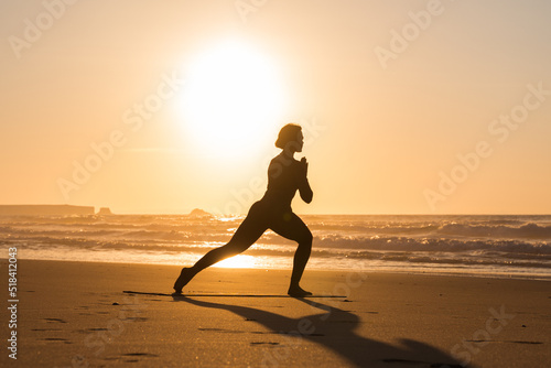 Calm woman doing yoga on the sandy beach near the ocean