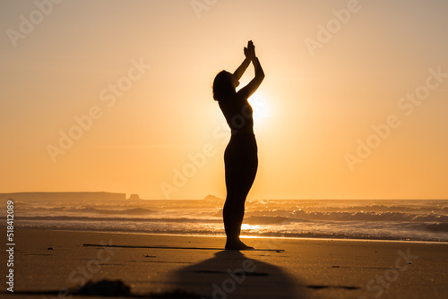 Young woman practicing yoga on sea beach during wonderful sunset