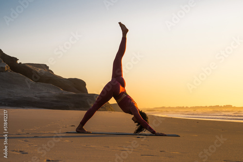 Caucasian woman stretching and practicing yoga asana while exercising at the beach