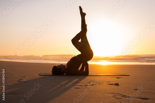 Young woman practicing inversion balancing yoga pose while standing at her back