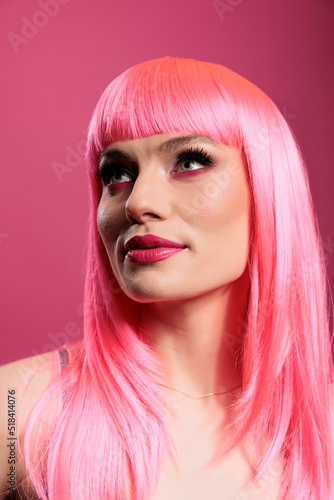 Portrait of female model with pink hair wig and trendy makeup posing in studio over background. Sexy carefree woman feeling attractive and beautiful in front of camera, fun glamour.