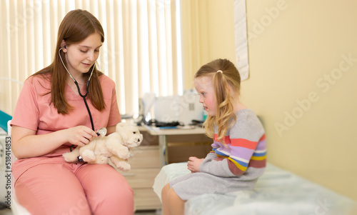 Nurse with stethoscope entertains 4 year old girl in clinic