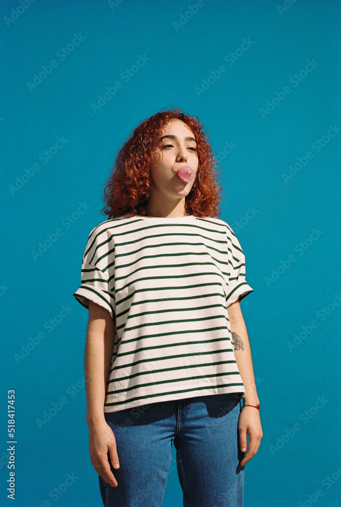 Cheerful woman blowing bubble gum in studio Cheerful woman blowing bubble gum in studio
