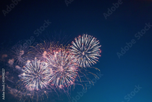 Colorful firework over the blue sky at night, White and red. Amateur photo. Noise. Grain