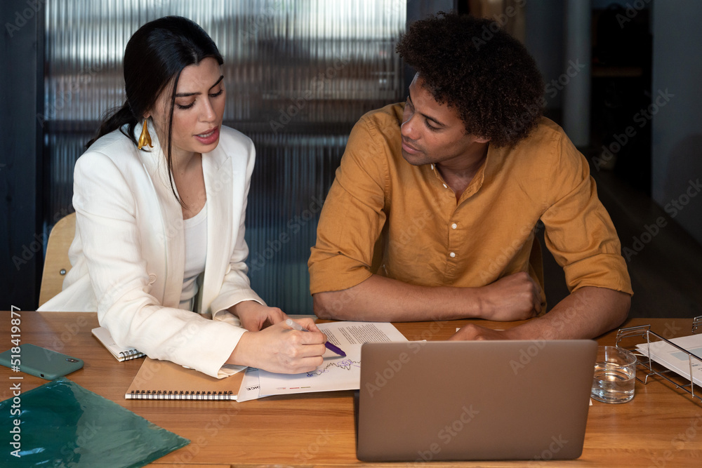 Diverse coworkers analyzing documents together Diverse coworkers analyzing documents together