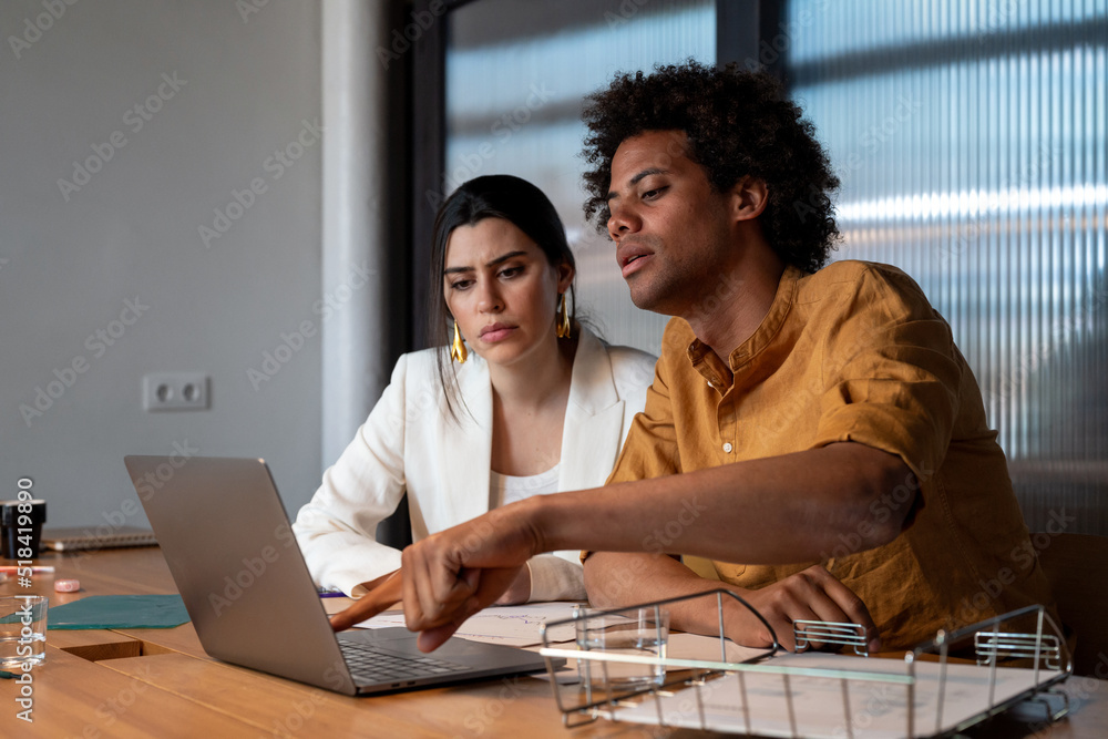 Multiracial colleagues analyzing data on laptop Multiracial colleagues analyzing data on laptop