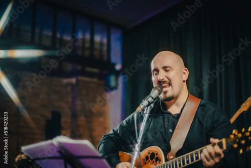 guitarist manplaying acoustic guitar and singing a song at a concert photo