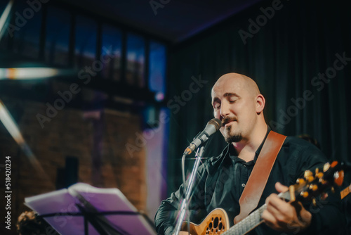 guitarist manplaying acoustic guitar and singing a song at a concert