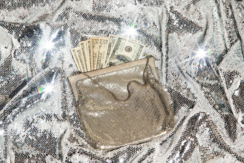 US dollar cash money in a glitz purse against glittering background