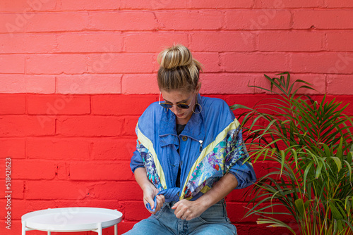 Young woman wearing a retro jacket sitting in front of a colorful wall photo