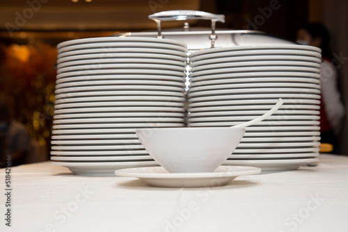 Group of white plates on a table with white tablecloth stacked and clean