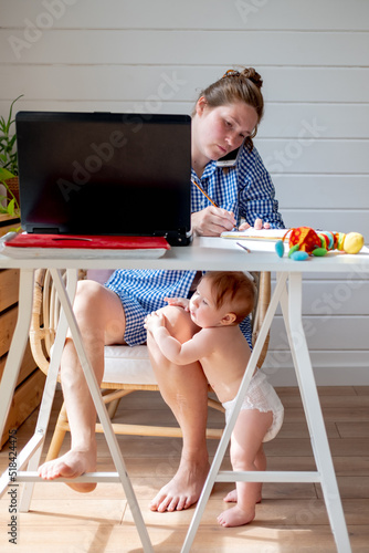 woman work at home while baby play photo