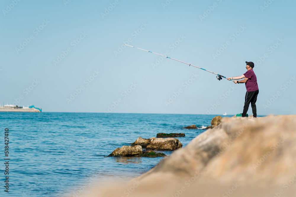 Fisherman pulling rod during fishing at seafront Fisherman pulling rod during fishing at seafront