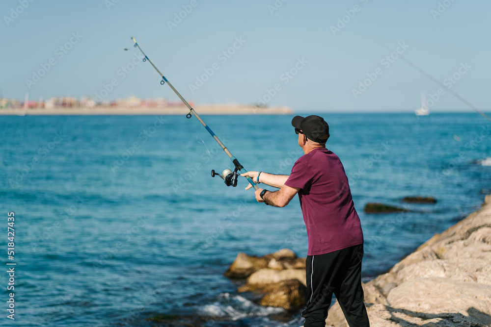 Skilled man catching fish from sea with rod Skilled man catching fish from sea with rod