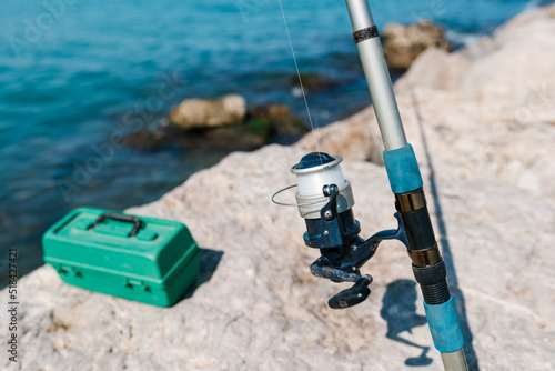 Fishing rod with reel and line near sea in sunlight photo