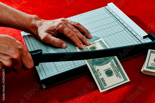 man is cutting a fake 100 dollar baknote photo