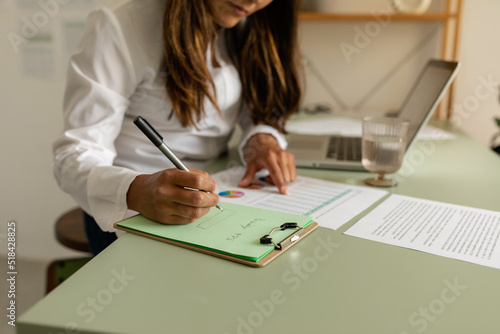 Accountant with statistical documents taking notes at office photo