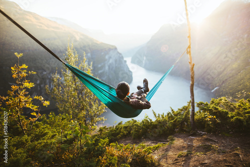 Man resting in hammock above fjord in Norway at sunset photo